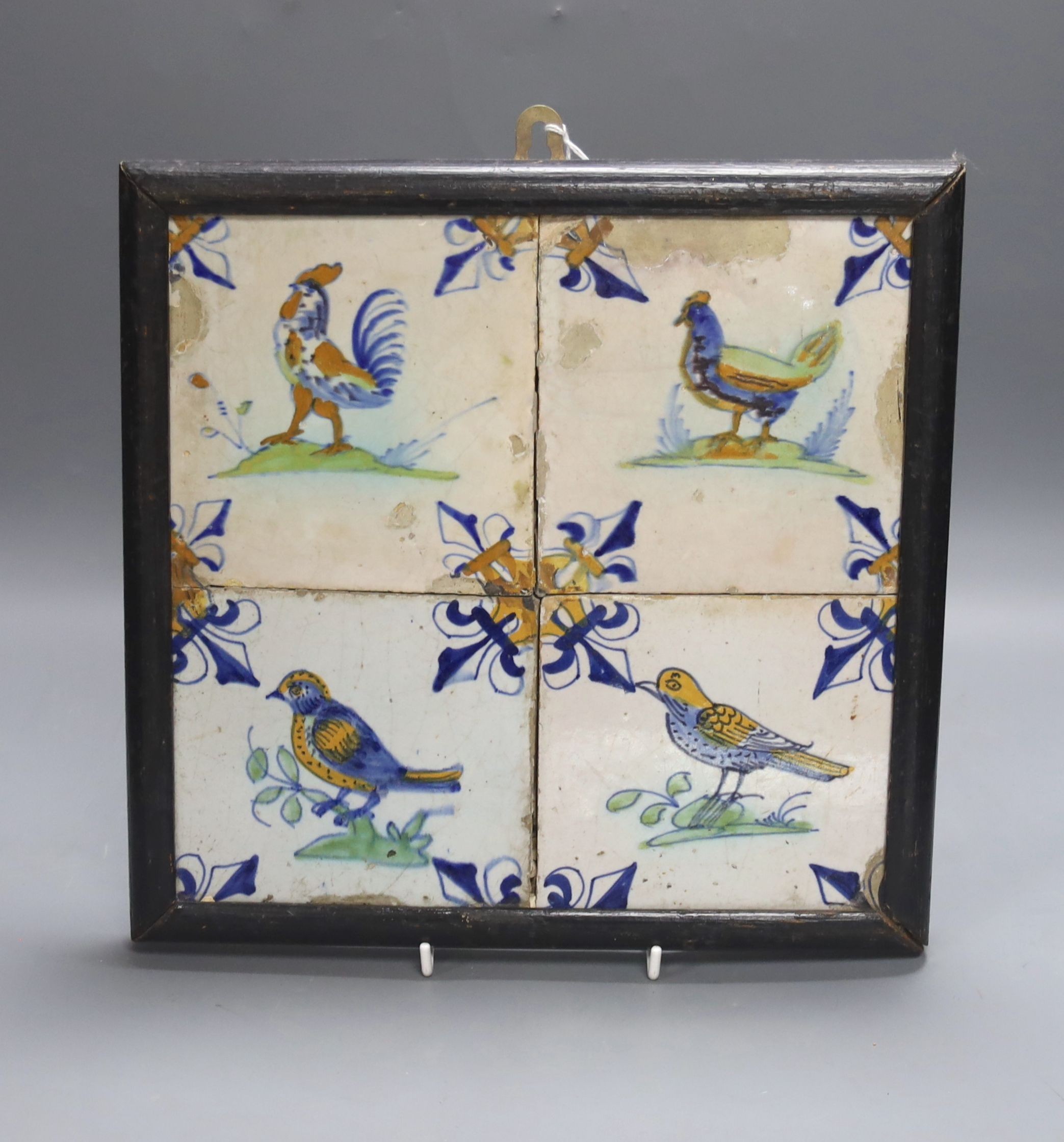 A 17th century Dutch delft four-tile panel, polychrome-decorated with birds and with fleur-de-lys to corners (frame 28cm)